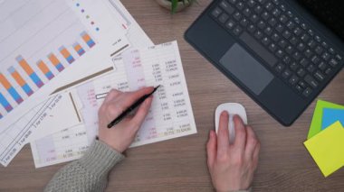 Ofiste, iş yapmak için gerekli eşyalarla birlikte bir kadının ellerini yakın plan çekeceğiz. Bir kız, bir hesap makinesi ve bilgisayar kullanarak, küresel bir mali raporun verilerini hesaplıyor. Yukarıdan görüntüle