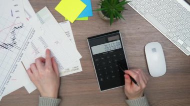 Ofiste, iş yapmak için gerekli eşyalarla birlikte bir kadının ellerini yakın plan çekeceğiz. Bir kız, bir hesap makinesi ve bilgisayar kullanarak, küresel bir mali raporun verilerini hesaplıyor. Yukarıdan görüntüle