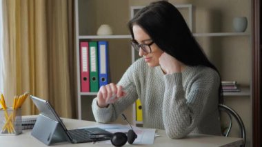 Genç, güzel iş kadını çalışıyor, bilgisayar teknolojisi kullanıyor, evde otururken internet sayfalarını karıştırıyor, iş raporlarında düzeltmeler yapıyor ve düzeltmeler yapıyor..