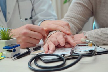 Doktorun elleri engelli bir hastanın ellerine masaj yapıyor. Kayıp parmak falanksları. Büyük pdlan.