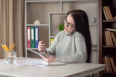 Ofiste çalışan genç ve güzel bir kız muhasebe tutanağı tutuyor..