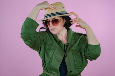 Hasır şapkalı olgun bir kadın. Pembe arkaplan.