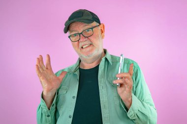 Ellerinde telefon olan yaşlı bir adam. Pembe arkaplan.