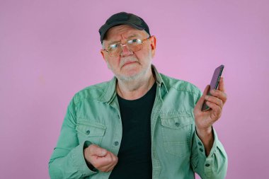 Ellerinde telefon olan yaşlı bir adam. Pembe arkaplan.