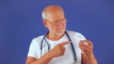 Stüdyoda mavi bir geçmişi olan yaşlı bir cerrah hastanın tıbbi geçmişiyle ilgileniyor ve uygun tedaviyi yazıyor. Yavaş çekim.