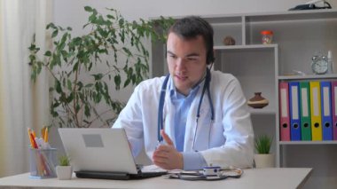 Genç bir stajyer doktor bir ofiste çalışır, bilgisayarla, hastalarla video bağlantısı yoluyla iletişim kurar, hastaların durumlarını ve tedavi yöntemlerini açıklar..