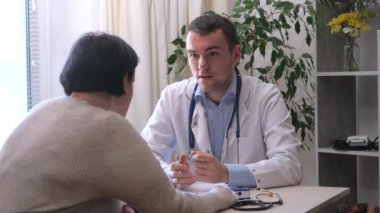 Ofiste genç bir doktor, orta yaşlı, engelli, parmakları olmayan bir kadını kabul ediyor, sağlık durumunu açıklıyor, teşhis koyuyor, uygun tedaviyi yazıyor ve hastaya manevi destek sağlıyor. Yavaş çekim.