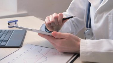 Hastanın tıbbi geçmişi üzerinde çalışan genç ve güzel bir doktorun elleri. Yavaş çekim.