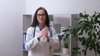 Steteskoplu ve bornozlu genç bir kadın, bir doktor, hastanedeki hastaların davranış kurallarını duygusal olarak açıklıyor. Yavaş çekim.