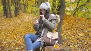 Doğada seyahat. Genç ve güzel bir kız, sonbahar ormanında, sonbahar doğasının güzelliğinden zevk alır, kulaklıkla müzik dinler, şarkıların ritmine kulak misafiri olur. Yavaş çekim.