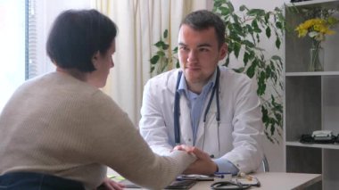 Ofiste genç bir doktor, orta yaşlı, engelli, parmakları olmayan bir kadını kabul ediyor, sağlık durumunu açıklıyor, teşhis koyuyor, uygun tedaviyi yazıyor ve hastaya manevi destek sağlıyor. Yavaş çekim.