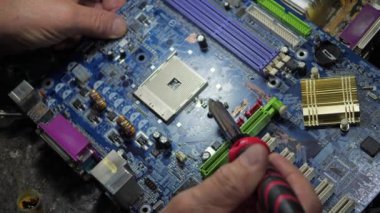 Yaşlı bir teknisyen, ölçüm aletleri ve teknik aletlerle atölyede bilgisayar donanımı tamir ediyor. Yavaş çekim.