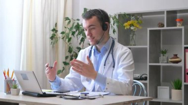 Genç bir stajyer doktor bir ofiste çalışır, bilgisayarla, hastalarla video bağlantısı yoluyla iletişim kurar, hastaların durumlarını ve tedavi yöntemlerini açıklar..