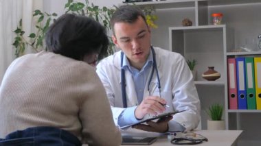 Ofiste genç bir doktor, orta yaşlı, engelli, parmakları olmayan bir kadını kabul ediyor, sağlık durumunu açıklıyor, teşhis koyuyor, uygun tedaviyi yazıyor ve hastaya manevi destek sağlıyor. Yavaş çekim.