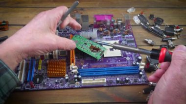 Atölyedeki ana kartı tamir et. Ustanın elleri, kullanım sürecindeki arızalar nedeniyle elektronik aletleri tamir edecek şekilde yakın plan çekimde. Yakın plan. Yavaş çekim.