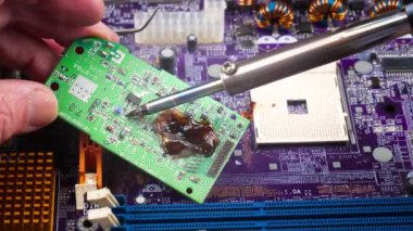 Atölyedeki ana kartı tamir et. Ustanın elleri, kullanım sürecindeki arızalar nedeniyle elektronik aletleri tamir edecek şekilde yakın plan çekimde. Yakın plan. Yavaş çekim.