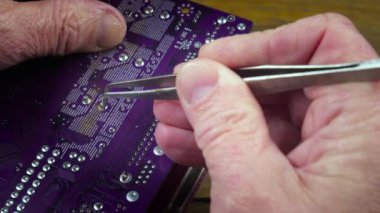 Atölyedeki ana kartı tamir et. Ustanın elleri, kullanım sürecindeki arızalar nedeniyle elektronik aletleri tamir edecek şekilde yakın plan çekimde. Yakın plan. Yavaş çekim.