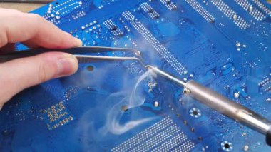 Atölyedeki ana kartı tamir et. Ustanın elleri, kullanım sürecindeki arızalar nedeniyle elektronik aletleri tamir edecek şekilde yakın plan çekimde. Yakın plan. Yavaş çekim.