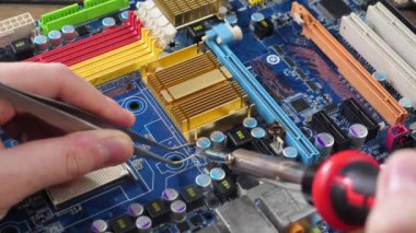 Atölyedeki ana kartı tamir et. Ustanın elleri, kullanım sürecindeki arızalar nedeniyle elektronik aletleri tamir edecek şekilde yakın plan çekimde. Yakın plan. Yavaş çekim.