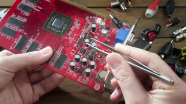 Atölyedeki ana kartı tamir et. Ustanın elleri, kullanım sürecindeki arızalar nedeniyle elektronik aletleri tamir edecek şekilde yakın plan çekimde. Yakın plan. Yavaş çekim.
