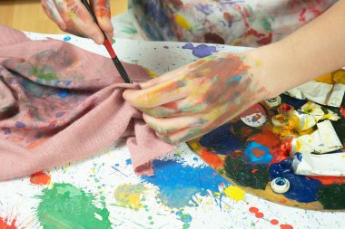 Boya paleti ve fırçalarla sanatçıların ellerine yakın çekim.