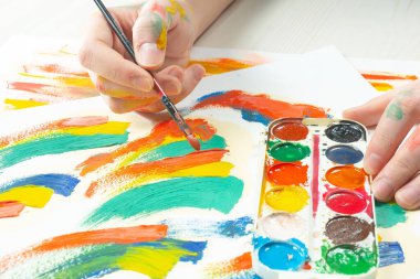 Boya paleti ve fırçalarla sanatçıların ellerine yakın çekim.