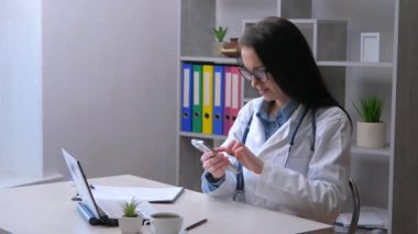 Steteskoplu ve laboratuvar önlüklü genç bir kadın hasta bir hastayı arıyor. İlaç kullanmanın kurallarını ona açıklıyor. Yavaş çekim.