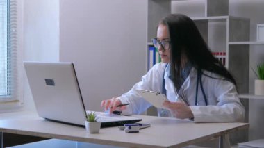 Steteskoplu ve laboratuvar önlüklü genç bir kadın hasta bir hastayı arıyor. İlaç kullanmanın kurallarını ona açıklıyor. Yavaş çekim.