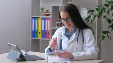 Steteskoplu ve laboratuvar önlüklü genç bir kadın hasta bir hastayı arıyor. İlaç kullanmanın kurallarını ona açıklıyor. Yavaş çekim.