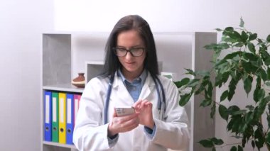 Steteskoplu ve laboratuvar önlüklü genç bir kadın hasta bir hastayı arıyor. İlaç kullanmanın kurallarını ona açıklıyor. Yavaş çekim.