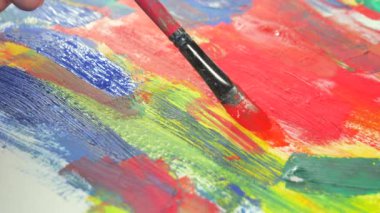 Sanatçının elleri, sanatta yaratıcı imgeler yaratmak için çalışır. Resim boyaları ve fırçalar, palet, guaj ve suluboya kullanarak tuvale çok renkli dokunuşlar uyguluyorlar..