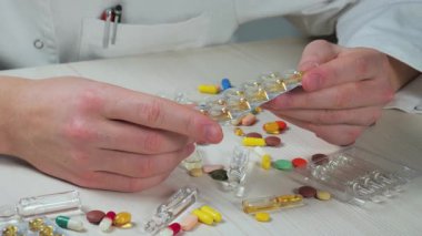 Genç bir doktor, bir hastalığı tedavi etmek için gerekli eylem derecesini ve uygulamayı inceleyerek hapları inceler. Yakın plan. Yavaş çekim.