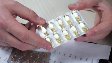 Genç bir doktor, bir hastalığı tedavi etmek için gerekli eylem derecesini ve uygulamayı inceleyerek hapları inceler. Yakın plan. Yavaş çekim.