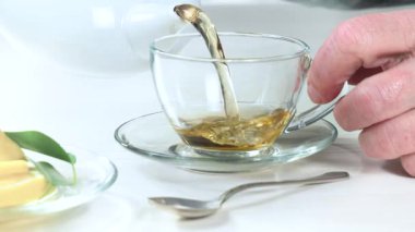 Yaşlı bir adam çaydanlıktan fincana çay doldurur. Yakın plan. Yavaş çekim.