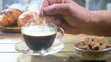 Yaşlı bir adam kahveyi kaşıkla karıştırır. Yakın plan. Yavaş çekim.