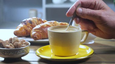 Yaşlı bir adam kahveyi kaşıkla karıştırır. Yakın plan. Yavaş çekim.