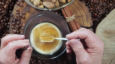 Yaşlı bir adam kahveyi kaşıkla karıştırır. Yakın plan. Yavaş çekim.