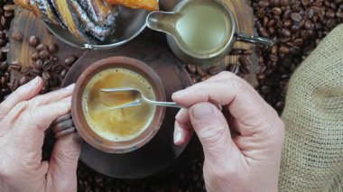 Yaşlı bir adam kahveyi kaşıkla karıştırır. Yakın plan. Yavaş çekim.