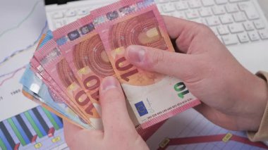 Genç bir finansörün elleri yavaşça parayı, avroyu kaydırıyor. Yavaş çekim.
