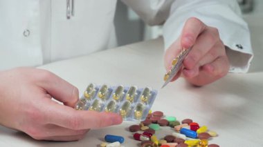 Genç bir doktor elinde haplar tutuyor, inceliyor, muayene ediyor. Yavaş çekim.