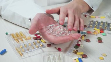 Genç bir doktor elinde enjeksiyon ampullerini tutuyor, inceliyor, inceliyor. Yavaş çekim.