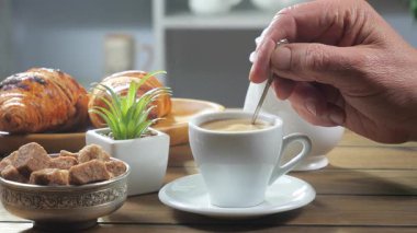 Yaşlı bir adamın elleri yavaşça sıcak espresso kahvesini kaşıkla karıştırıyor. Yavaş çekim.