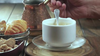 Yaşlı bir adamın elleri yavaşça sıcak espresso kahvesini kaşıkla karıştırıyor. Yavaş çekim.