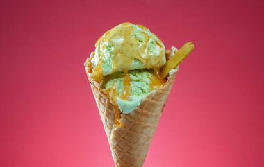 Kırmızı arka planda renkli serpiştirilmiş dondurma külahı. Kapat..