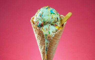 Kırmızı arka planda renkli serpiştirilmiş dondurma külahı. Kapat..