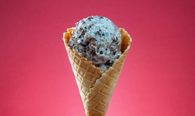 Kırmızı arka planda renkli serpiştirilmiş dondurma külahı. Kapat..