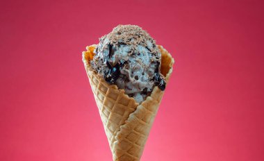 Kırmızı arka planda renkli serpiştirilmiş dondurma külahı. Kapat..