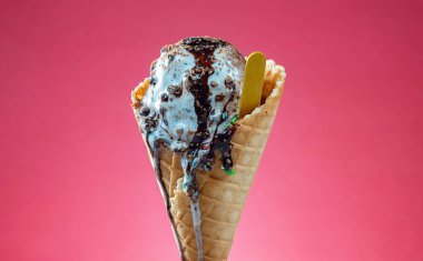 Kırmızı arka planda renkli serpiştirilmiş dondurma külahı. Kapat..