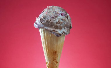 Kırmızı arka planda renkli serpiştirilmiş dondurma külahı. Kapat..