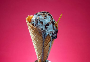 Kırmızı arka planda renkli serpiştirilmiş dondurma külahı. Kapat..